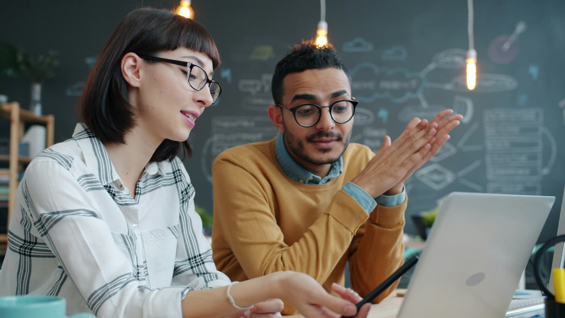 Two software teammates reviewing a project together on a laptop